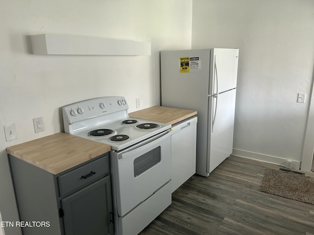 kitchen with white appliances, visible vents, baseboards, dark wood finished floors, and butcher block counters