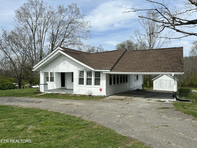 view of front of property with a front lawn, driveway, and a shingled roof