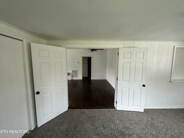 spare room with visible vents, dark carpet, and ceiling fan