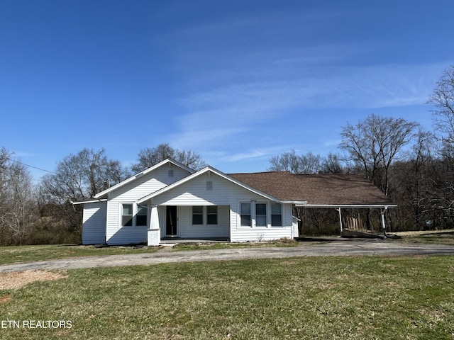 view of front facade featuring driveway, a front yard, and a shingled roof