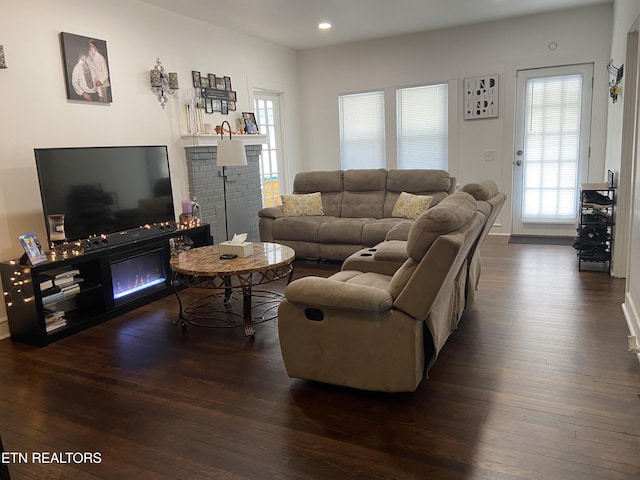 living room with recessed lighting, dark wood-type flooring, and a glass covered fireplace