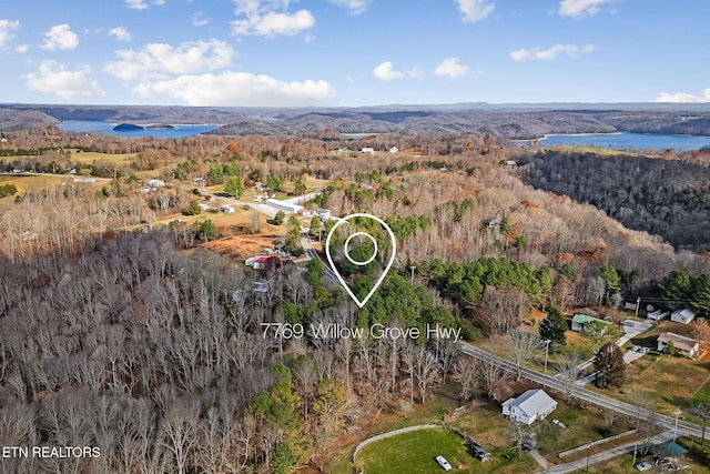 aerial view with a water view and a wooded view