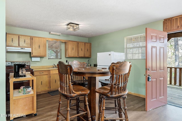 dining area featuring baseboards, a textured ceiling, and wood finished floors