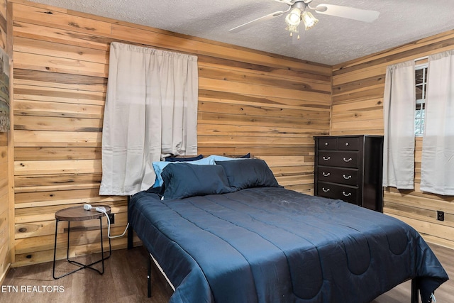 bedroom featuring a ceiling fan, wooden walls, wood finished floors, and a textured ceiling