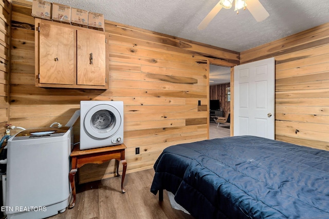 bedroom featuring ceiling fan, wood finished floors, wood walls, and a textured ceiling