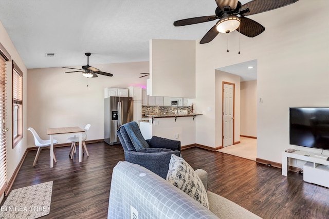 living area with visible vents, lofted ceiling, dark wood-type flooring, and baseboards