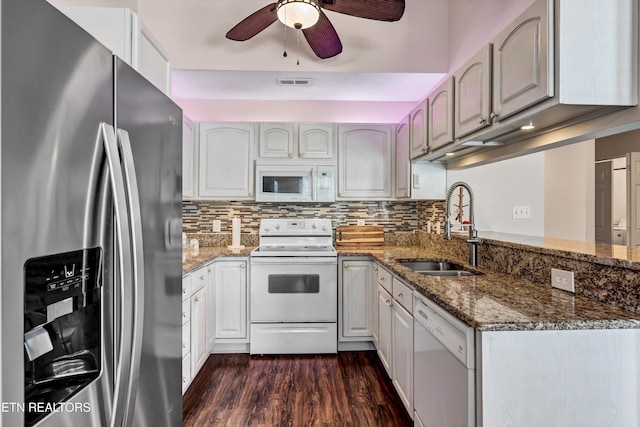 kitchen featuring white appliances, dark wood-style floors, visible vents, a sink, and backsplash