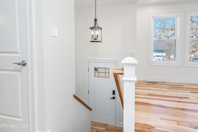 entryway featuring crown molding, baseboards, and light wood finished floors