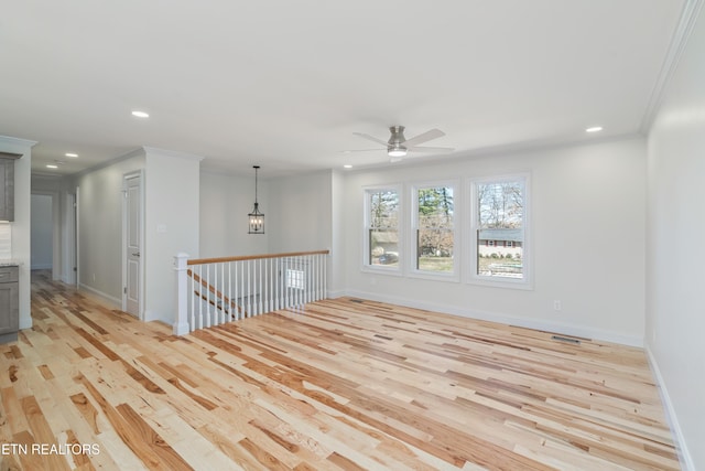 empty room with ceiling fan with notable chandelier, recessed lighting, light wood-style floors, and ornamental molding