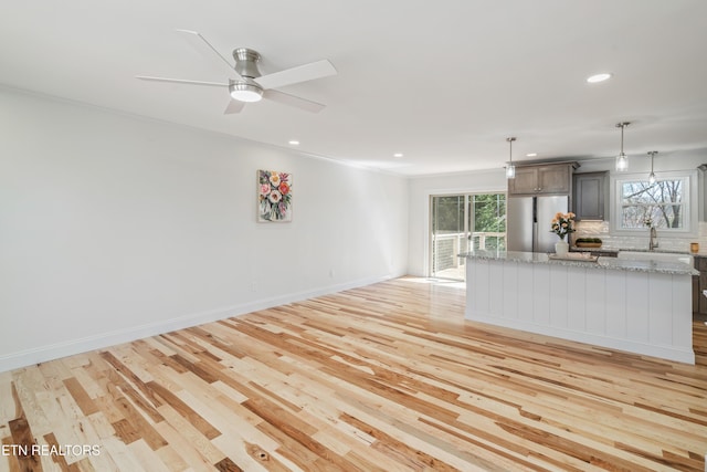 kitchen with tasteful backsplash, stainless steel refrigerator, light wood-style flooring, and a kitchen island