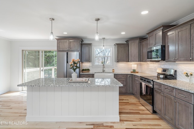 kitchen featuring light wood-style flooring, appliances with stainless steel finishes, a center island, and a sink