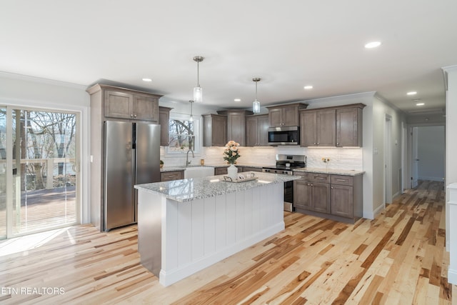 kitchen with decorative backsplash, light wood-style flooring, ornamental molding, and stainless steel appliances