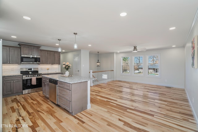 kitchen featuring open floor plan, light wood-style floors, appliances with stainless steel finishes, crown molding, and decorative backsplash