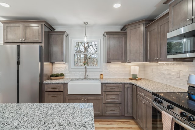 kitchen with a sink, stainless steel appliances, light stone countertops, and tasteful backsplash