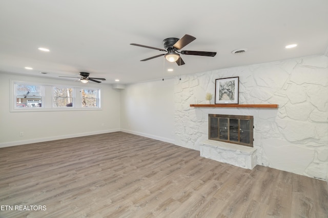 unfurnished living room featuring a ceiling fan, wood finished floors, visible vents, and a fireplace