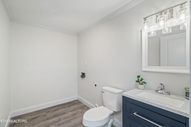 bathroom featuring baseboards, toilet, ornamental molding, wood finished floors, and vanity