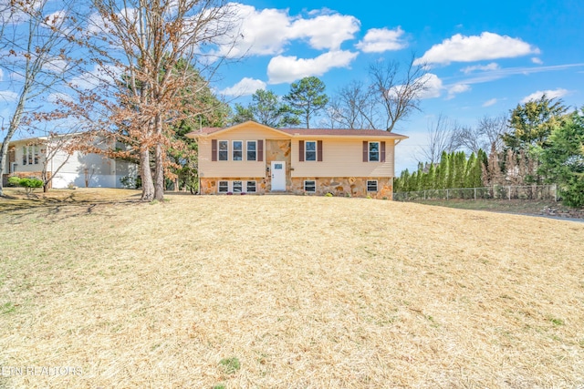 raised ranch featuring a front yard and fence