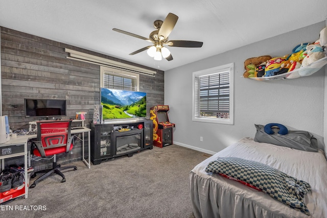 carpeted bedroom with wooden walls, ceiling fan, and baseboards