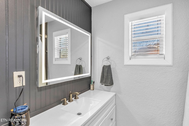 bathroom featuring vanity, plenty of natural light, and a textured wall