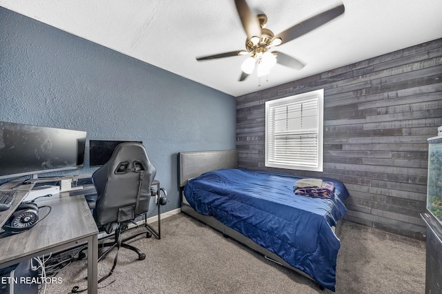 bedroom with carpet, wooden walls, baseboards, ceiling fan, and a textured wall