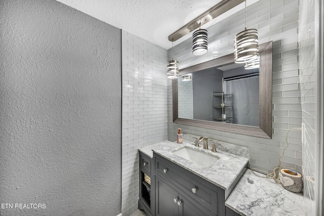 bathroom featuring backsplash, a textured ceiling, vanity, and a textured wall