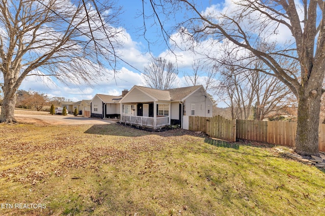 view of front facade with fence, a porch, a chimney, concrete driveway, and a front lawn