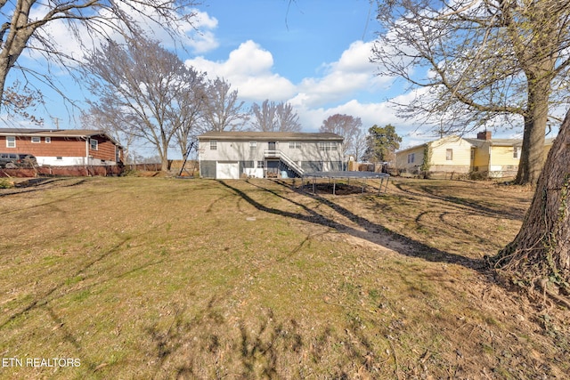 rear view of property featuring a lawn and a trampoline