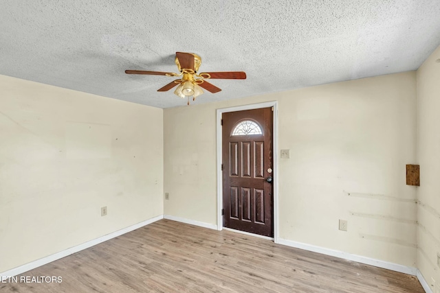 foyer with ceiling fan, baseboards, a textured ceiling, and wood finished floors