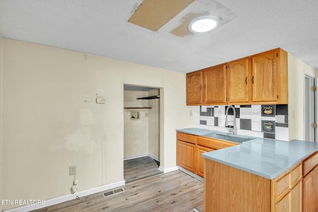 kitchen with a sink, visible vents, light countertops, and light wood finished floors