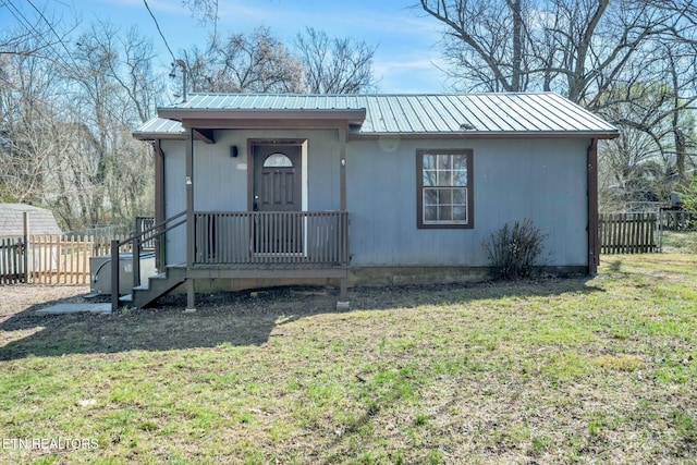 view of front facade with a front yard, fence, and metal roof