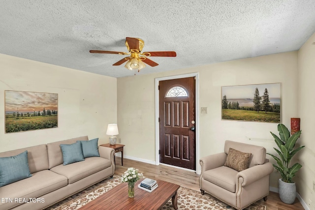 living area with baseboards, a textured ceiling, a ceiling fan, and wood finished floors