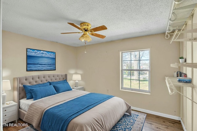 bedroom featuring a ceiling fan, wood finished floors, baseboards, and a textured ceiling