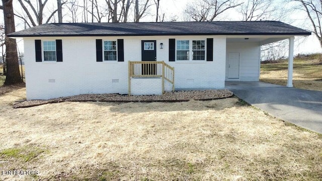 ranch-style home featuring a carport, brick siding, driveway, and crawl space