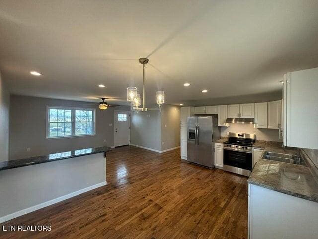 kitchen featuring baseboards, under cabinet range hood, appliances with stainless steel finishes, dark wood-style floors, and white cabinets