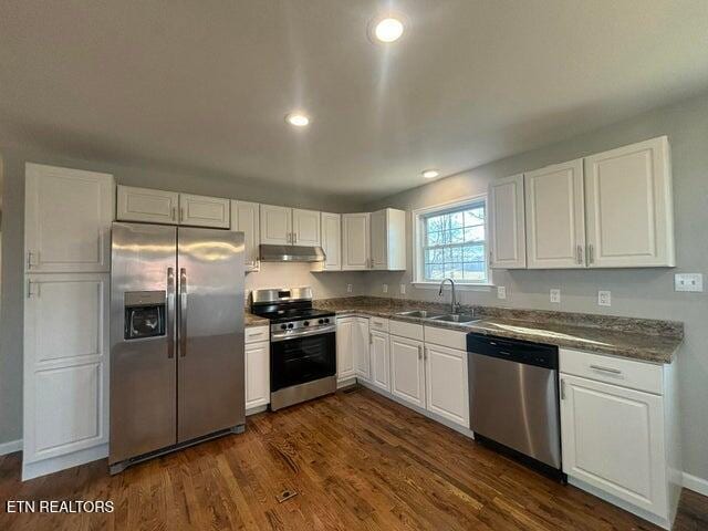 kitchen featuring dark wood-style flooring, a sink, stainless steel appliances, white cabinets, and under cabinet range hood