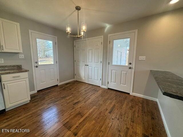 interior space with a chandelier, baseboards, and dark wood finished floors