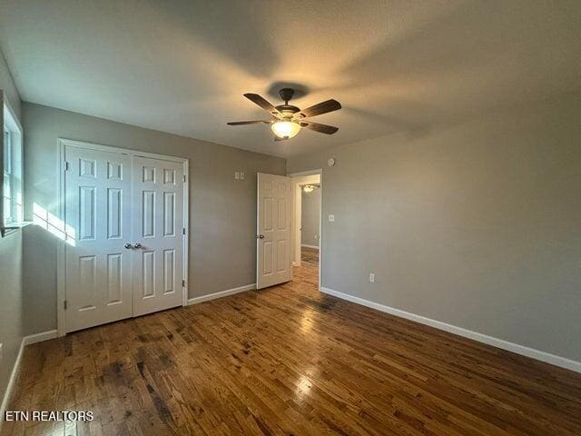 unfurnished bedroom with wood finished floors, baseboards, and a closet