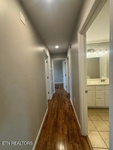 corridor featuring a sink, light wood-type flooring, and baseboards