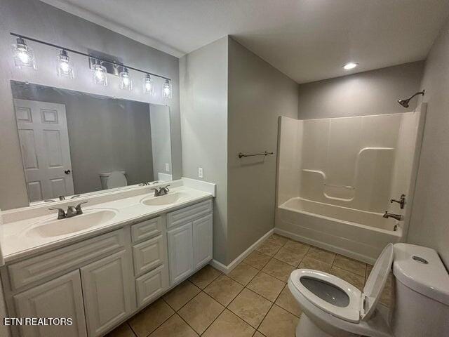 bathroom featuring double vanity, a sink, tile patterned flooring, shower / bathing tub combination, and toilet