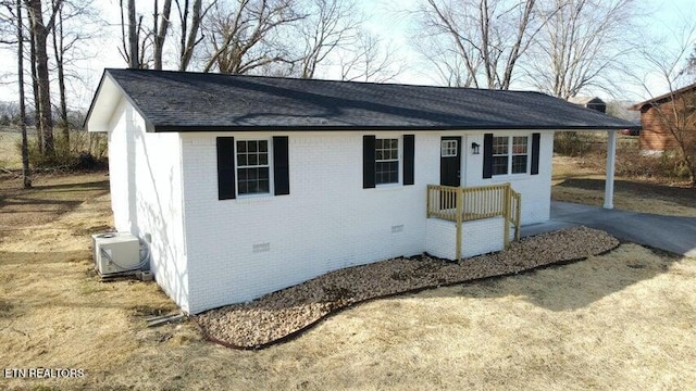 view of front of home featuring driveway, a shingled roof, crawl space, ac unit, and brick siding