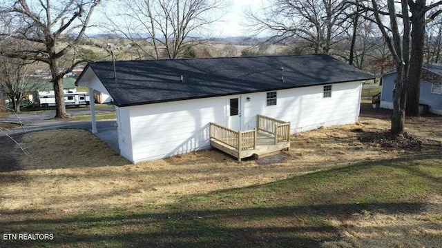 rear view of house with a shingled roof and a yard