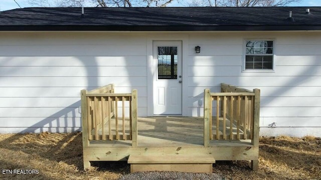 property entrance featuring a wooden deck and roof with shingles