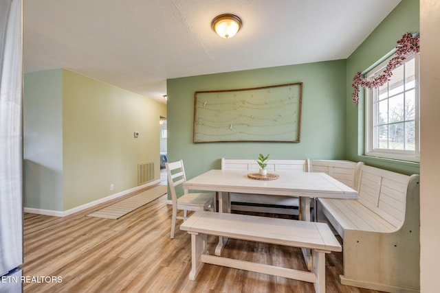 dining room with baseboards, light wood finished floors, and visible vents