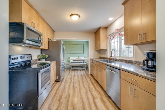 kitchen with light wood-style flooring, recessed lighting, a sink, dark countertops, and appliances with stainless steel finishes
