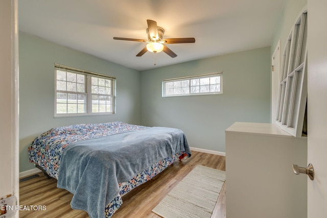 bedroom featuring ceiling fan, baseboards, visible vents, and wood finished floors