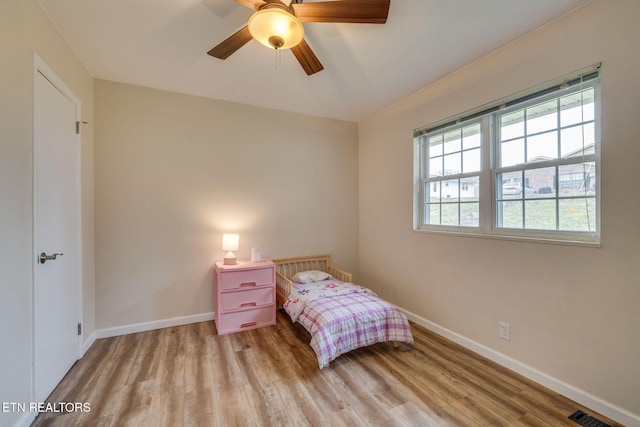 bedroom with baseboards, ceiling fan, visible vents, and wood finished floors