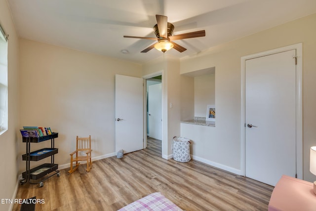 interior space featuring a ceiling fan, baseboards, and wood finished floors