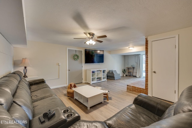 living area with a textured ceiling, baseboards, a ceiling fan, and light wood-style floors