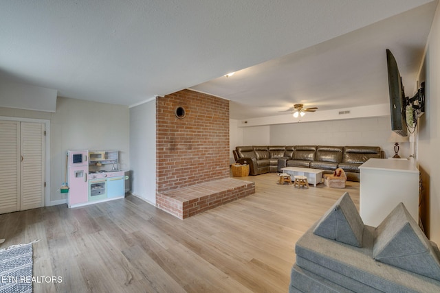 living room with visible vents, light wood-style flooring, and a ceiling fan
