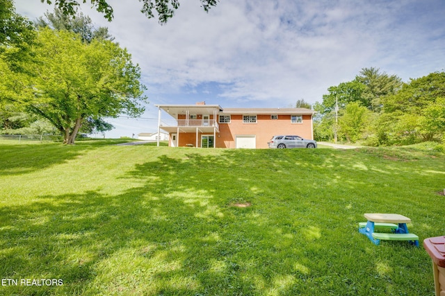 rear view of property featuring a chimney, fence, a lawn, and a balcony